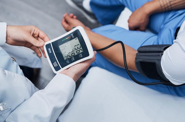 Doctor placing a blood pressure cuff on a patient's arm during a visit Doctor placing a blood pressure cuff on a patient's arm during a visit
