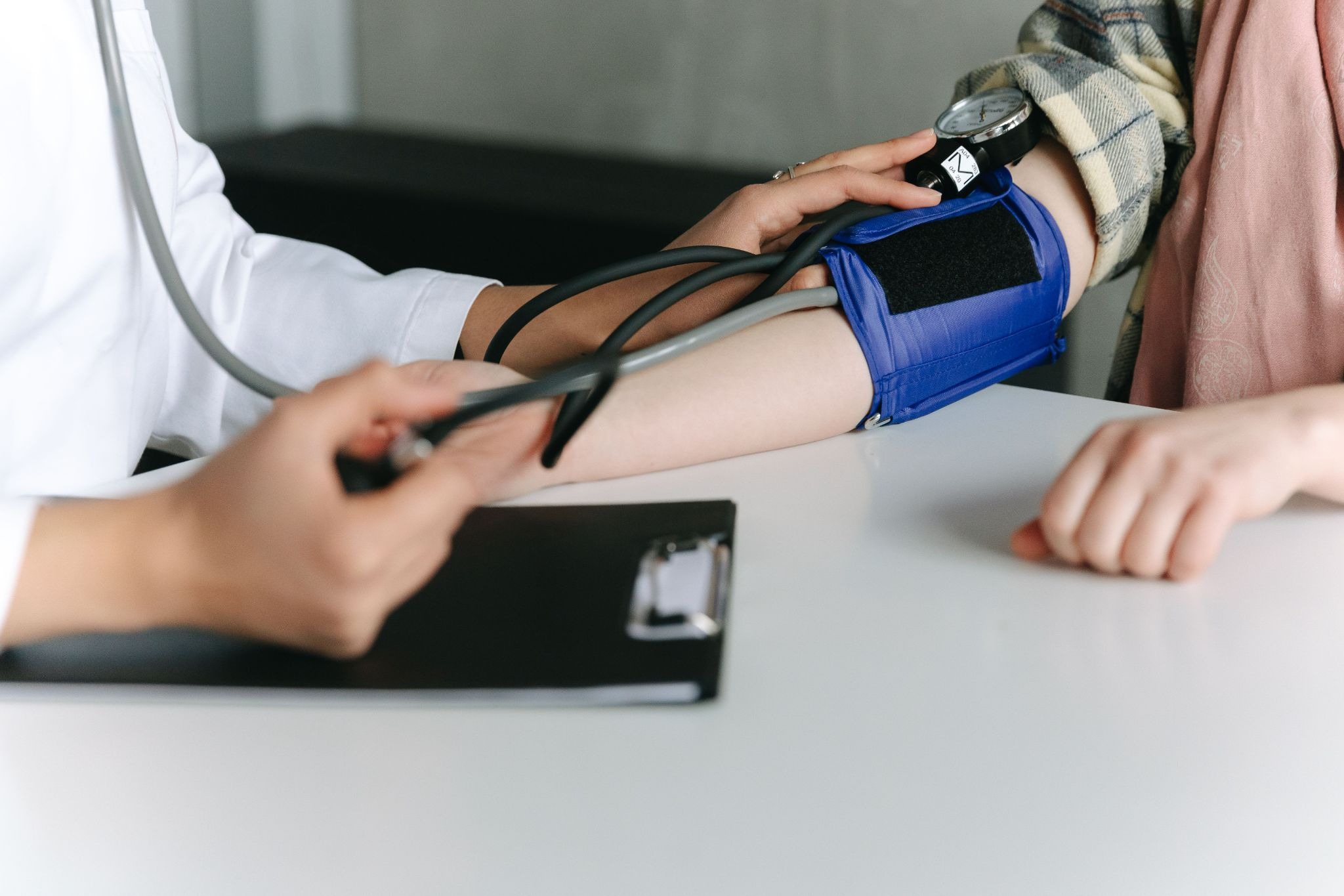Doctor holding a digital blood pressure monitor while checking a patient's blood pressure